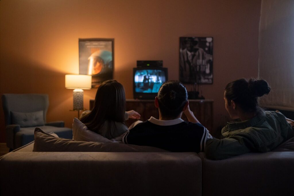 Trois personnes sur un canapé regardant un film sur le téléviseur du salon