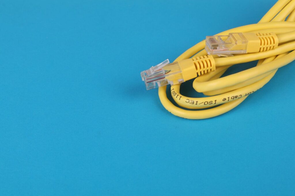 Câble réseau Ethernet jaune enroulé sur un fond bleu uni