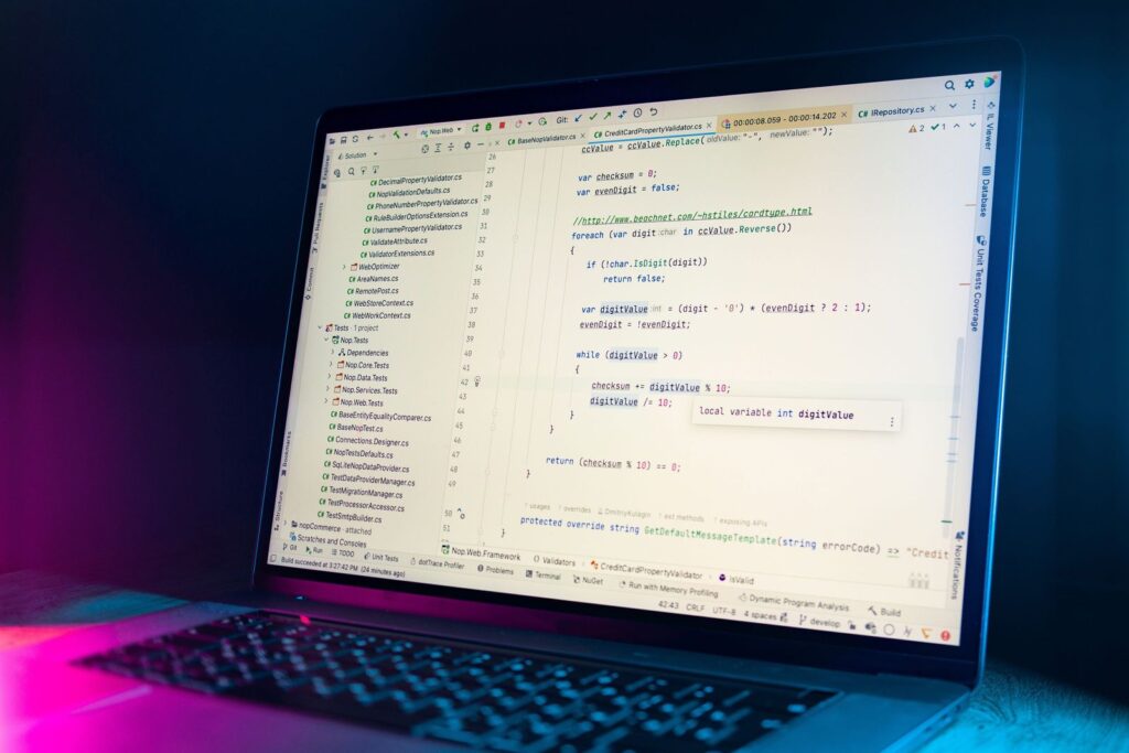 Écran d'ordinateur portable affichant un éditeur de code dans une pièce faiblement éclairée