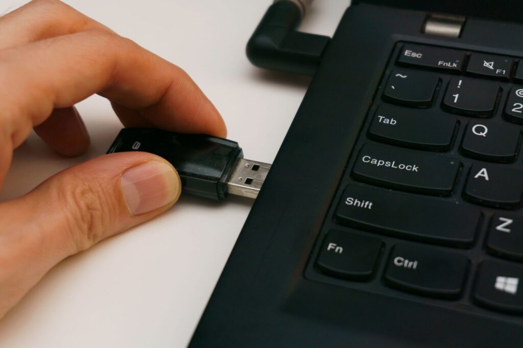 Clé USB insérée dans le port d'un ordinateur portable posé sur une surface blanche