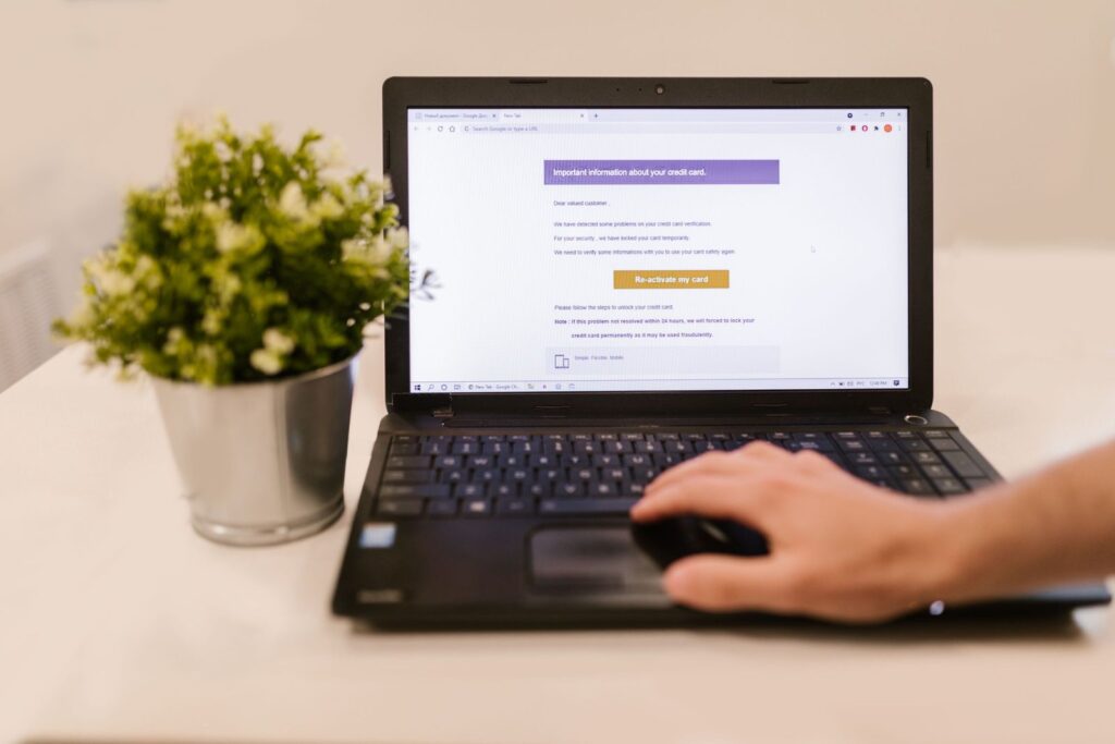 Ordinateur portable affichant une boîte de réception d'e-mails sur un bureau, à côté d'une plante en pot